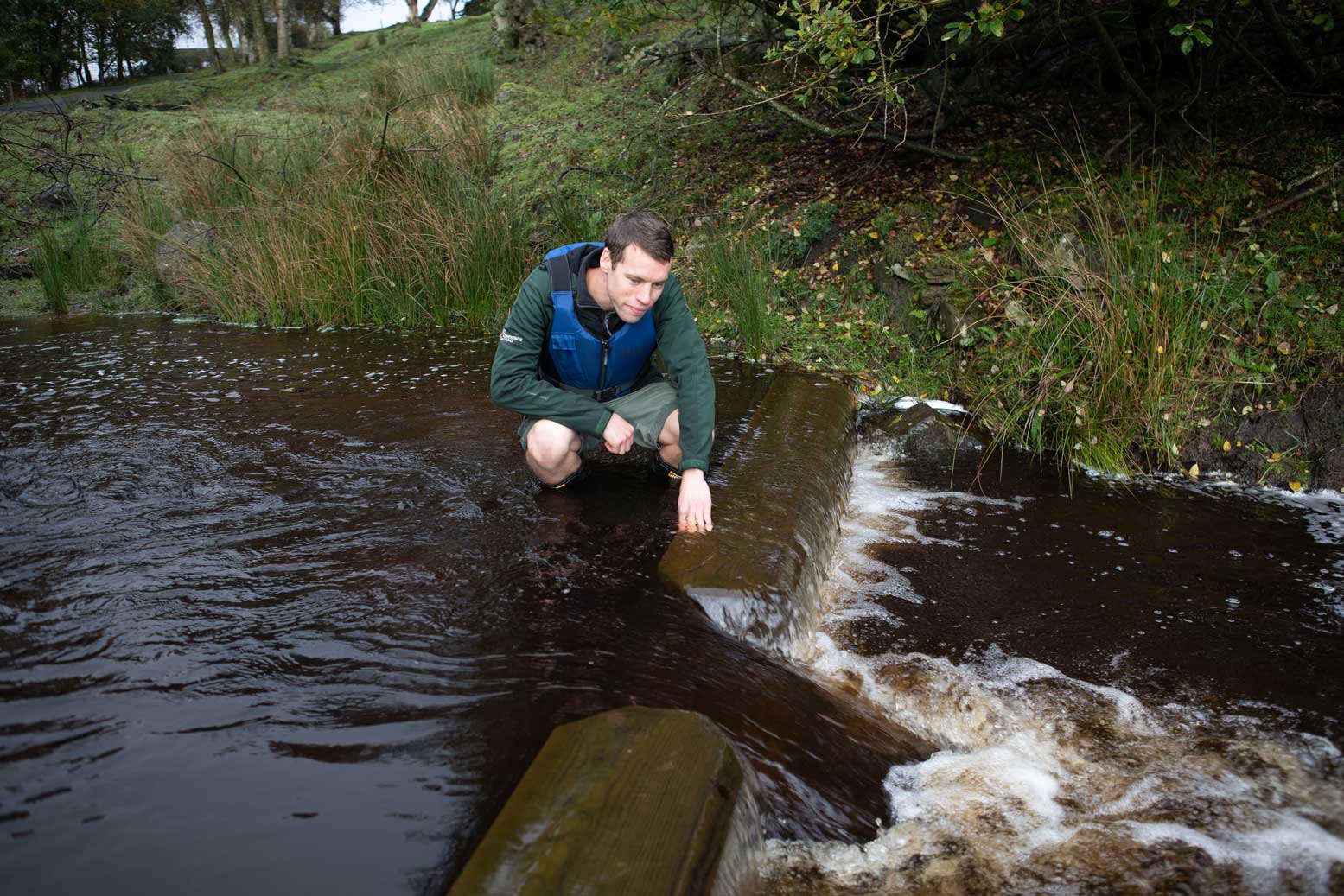Person looking at a newly installed wooden weir in a river. Credit Charlie Fox.
