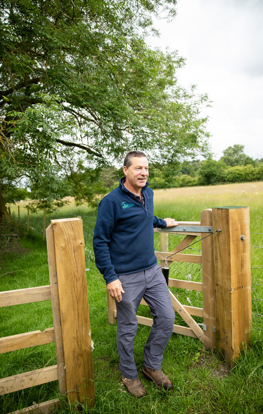 Newly created self-closing wooden gate in the landscape. Person is walking through the gate. Credit Charlie Fox.